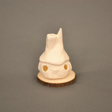 A white porcelain cottage made out of clay. It has a pointed roof and chimey with circular windows in front and a door.